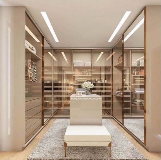 Closet planejado da Montari com portas de vidro bronze e iluminação embutida
