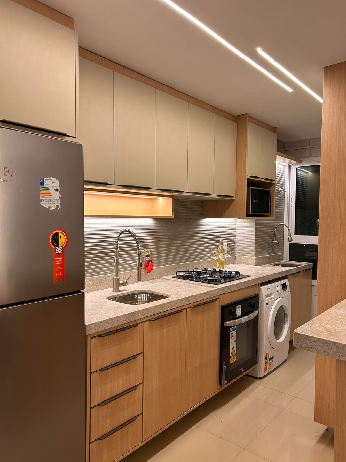 Cozinha planejada compacta com iluminação linear no teto